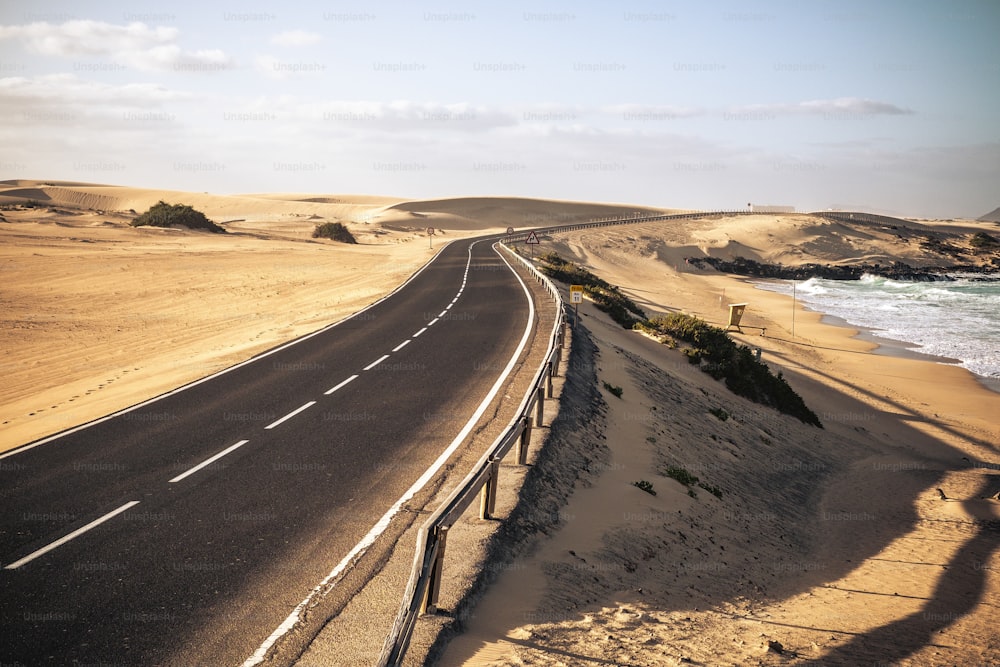 Long black asphalt road with desert and beach around for travel and adventure summer lifestyle concept with nobody traveling and no traffic cars - beautiful adventure places to discover