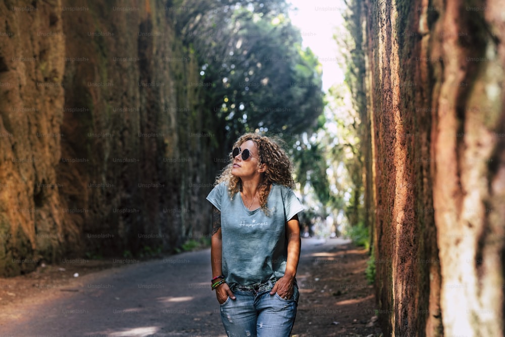 Beautiful woman walk in the park enjoying outdoor leisure activity in scenic forest place - concept of people and nature connection lifestyle with happy tourist female