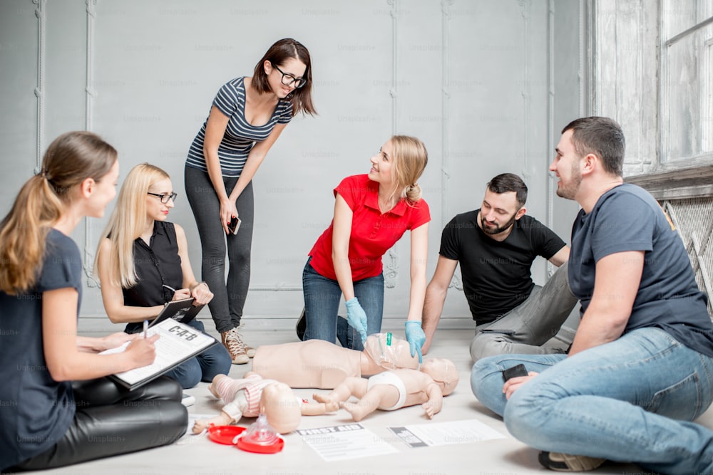 Une jeune instructrice montre comment rejeter la tête des mannequins pour respirer lors de la formation de groupe de premiers secours à l’intérieur