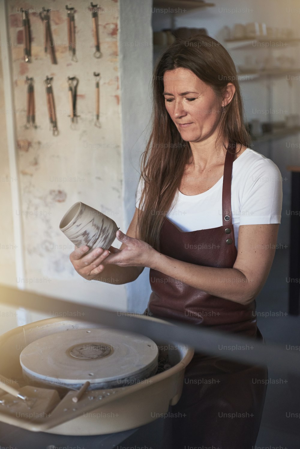 Female artisan standing alone in her creative ceramic studio inspecting a creatively crafted piece of pottery