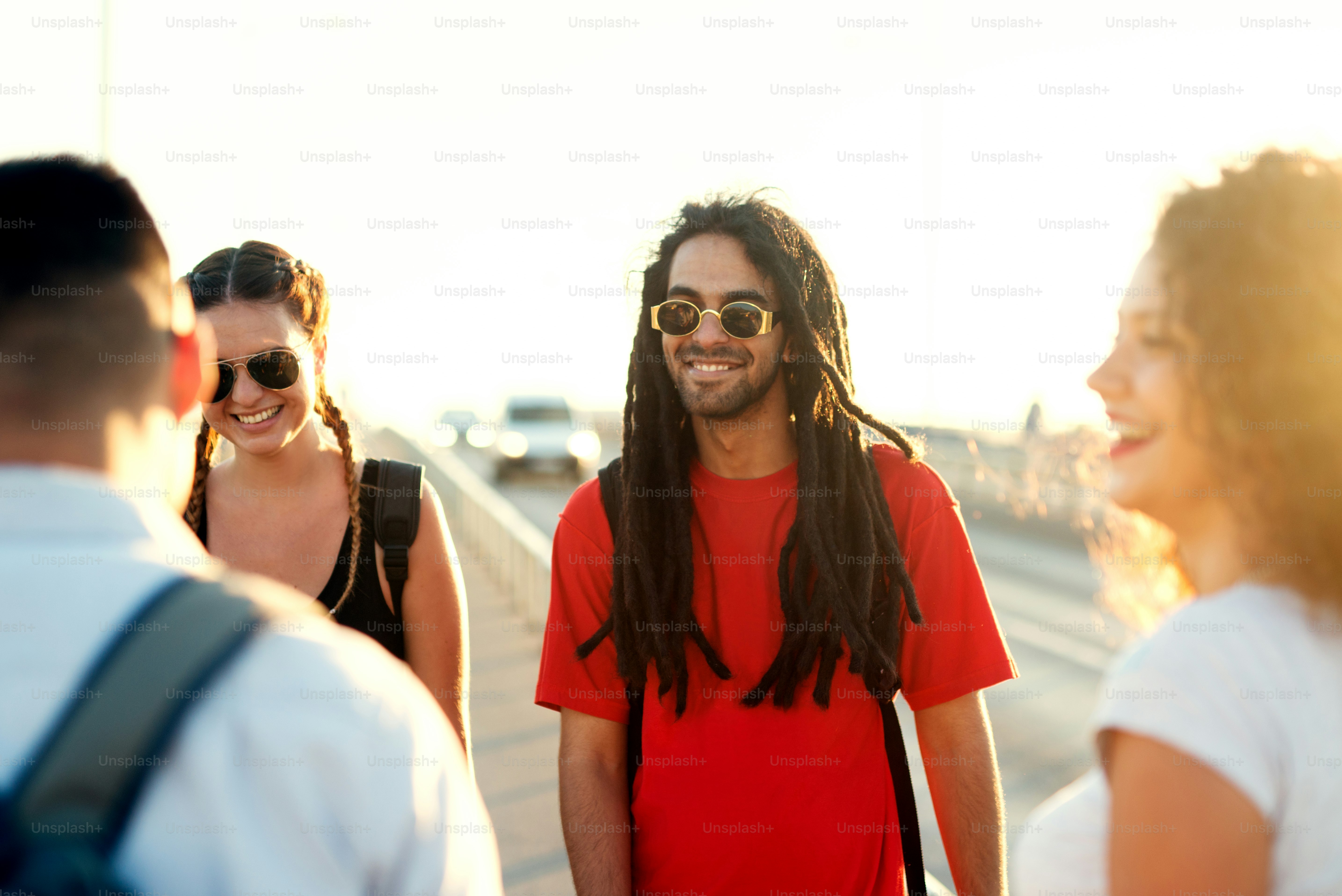 Young handyman with dreadlocks and sunglasses having fun with friends ...