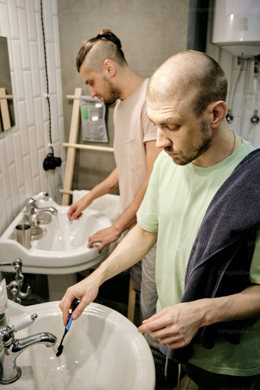 two young gay men washing toothbrushes after brushing teeth