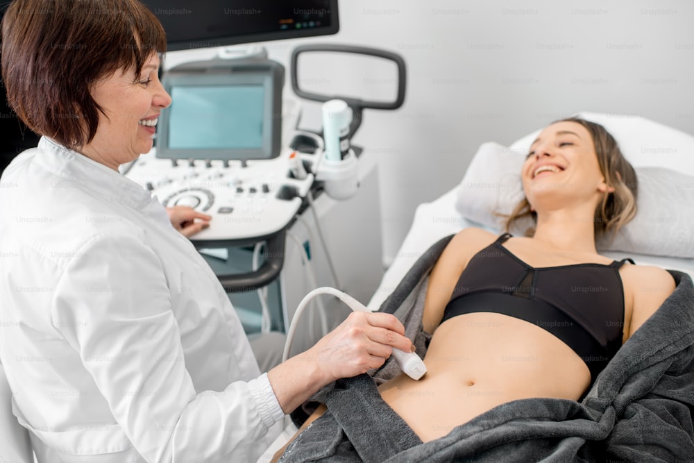 Senior doctor making an ultrasound examination to a young woman patient