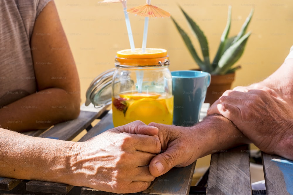 Zwei ältere Menschen trinken an einem sonnigen Tag Hand in Hand auf dem Terrassenfeld