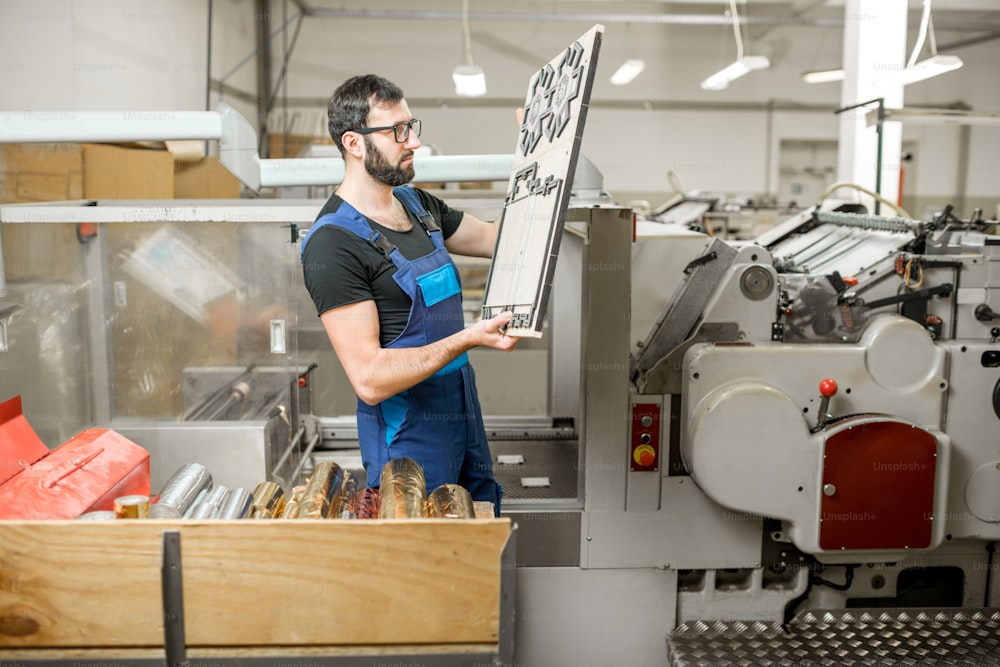 Trabalhador em pé com clichê para cortar caixas na fabricação de impressão vintage