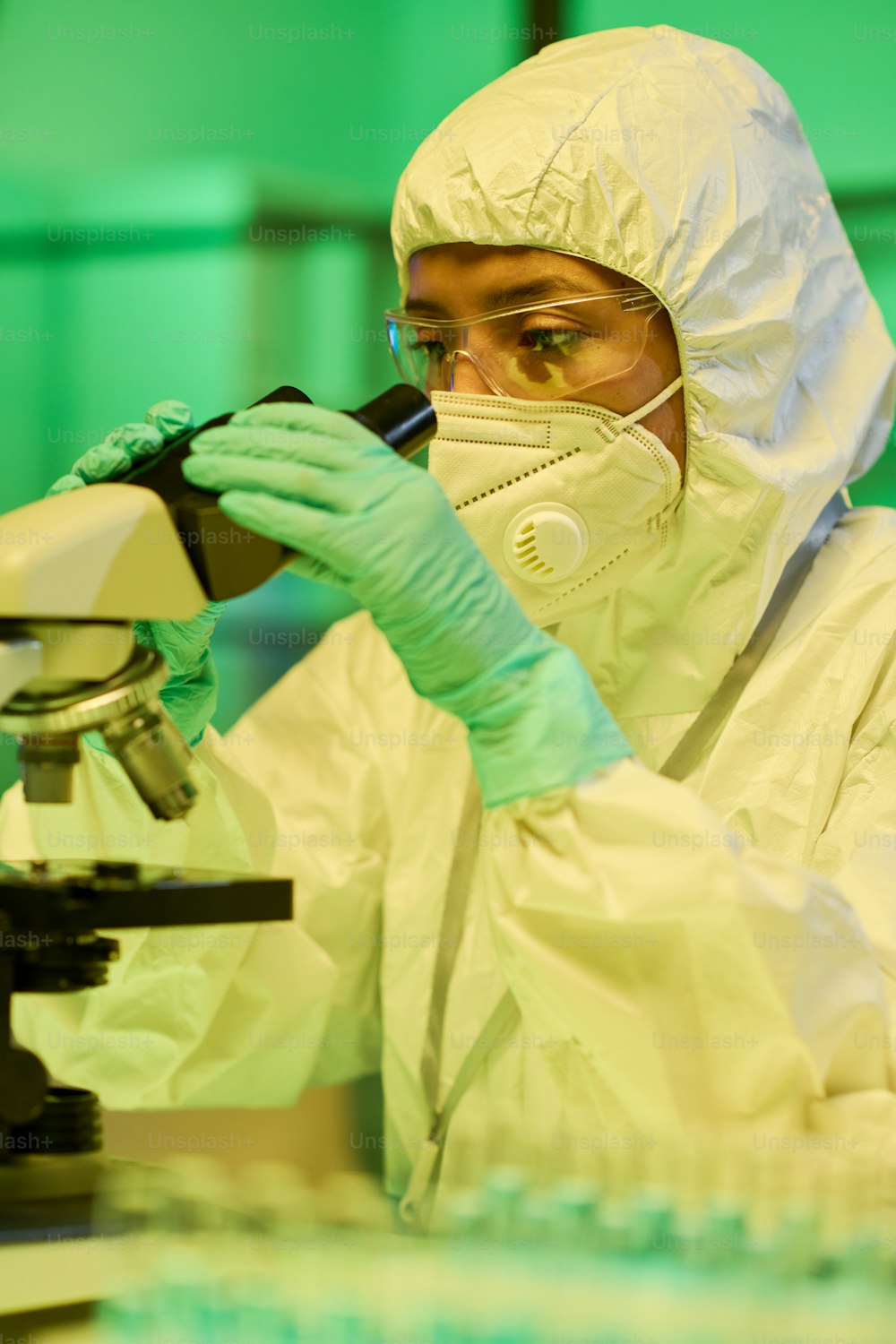 Giovane lavoratore di laboratorio contemporaneo in tute protettive, guanti e respiratore che studia le caratteristiche del nuovo ceppo di coronavirus