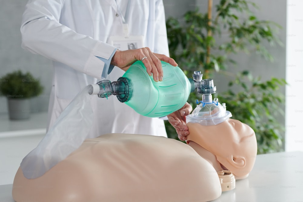 Gros plan d’un travailleur de la santé utilisant un masque à oxygène pour la respiration tout en s’entraînant sur un mannequin