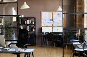 Image of modern office with workplaces of employees with computers on them and board with documents hanging on wall