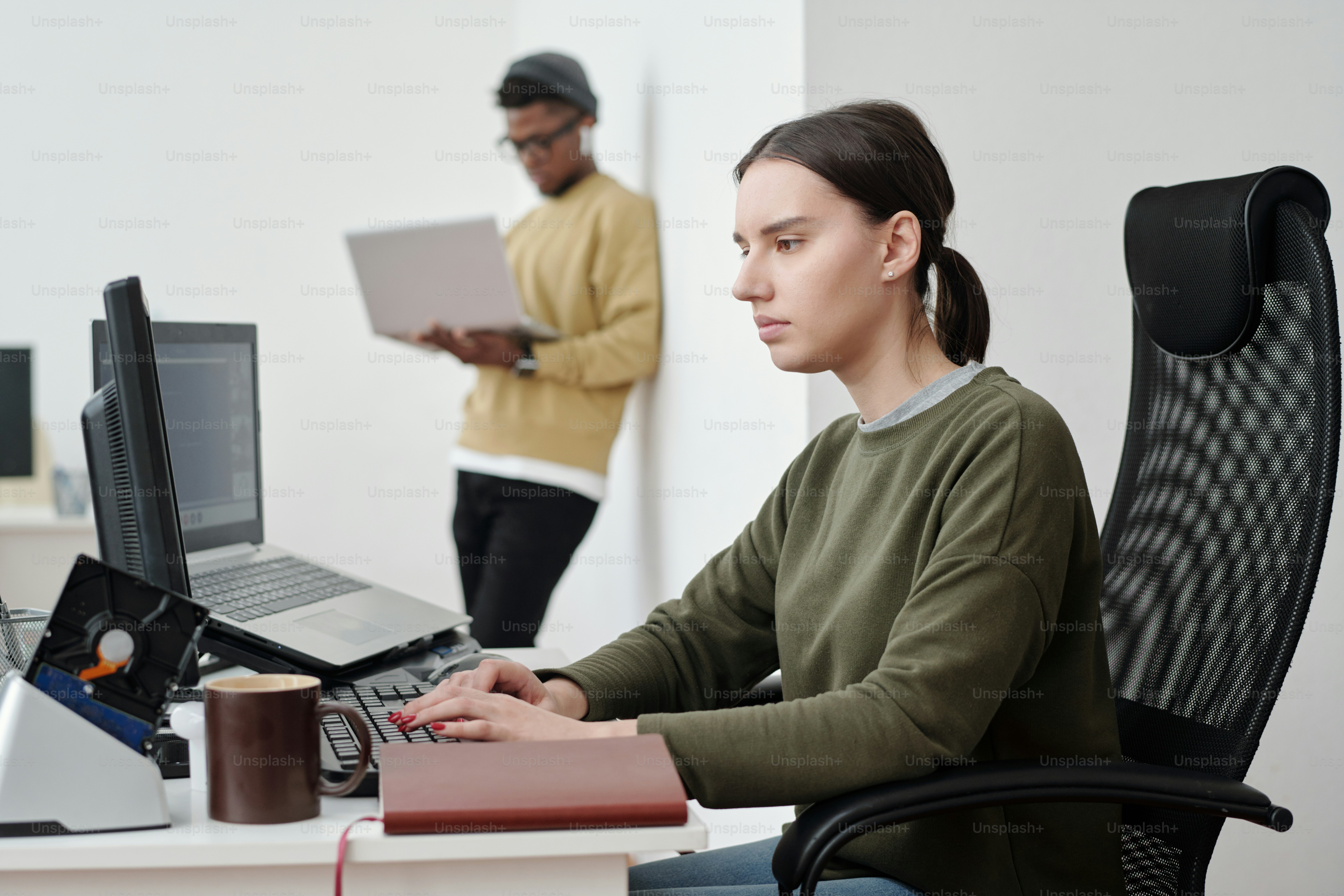 Young serious female programmer in casualwear looking at computer ...