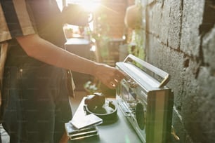 Close-up of girl in stylish casualwear choosing musical station while turning amplifier on portable radio receiver in the morning