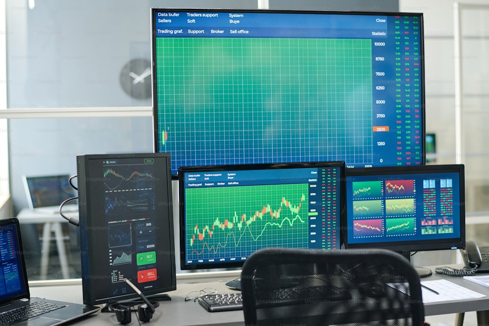 Horizontal no people shot of modern investment specialists workspace with desktop computers and monitors with graphs on screens in modern office