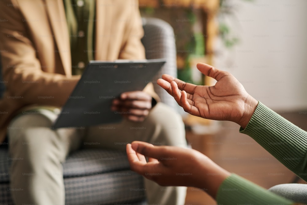 Hands of young black woman describing her mental problem to counselor sitting in front of her during psychological session