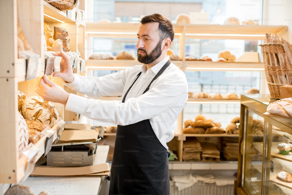 Seller making arrangements on the shelves in the store with bakery products