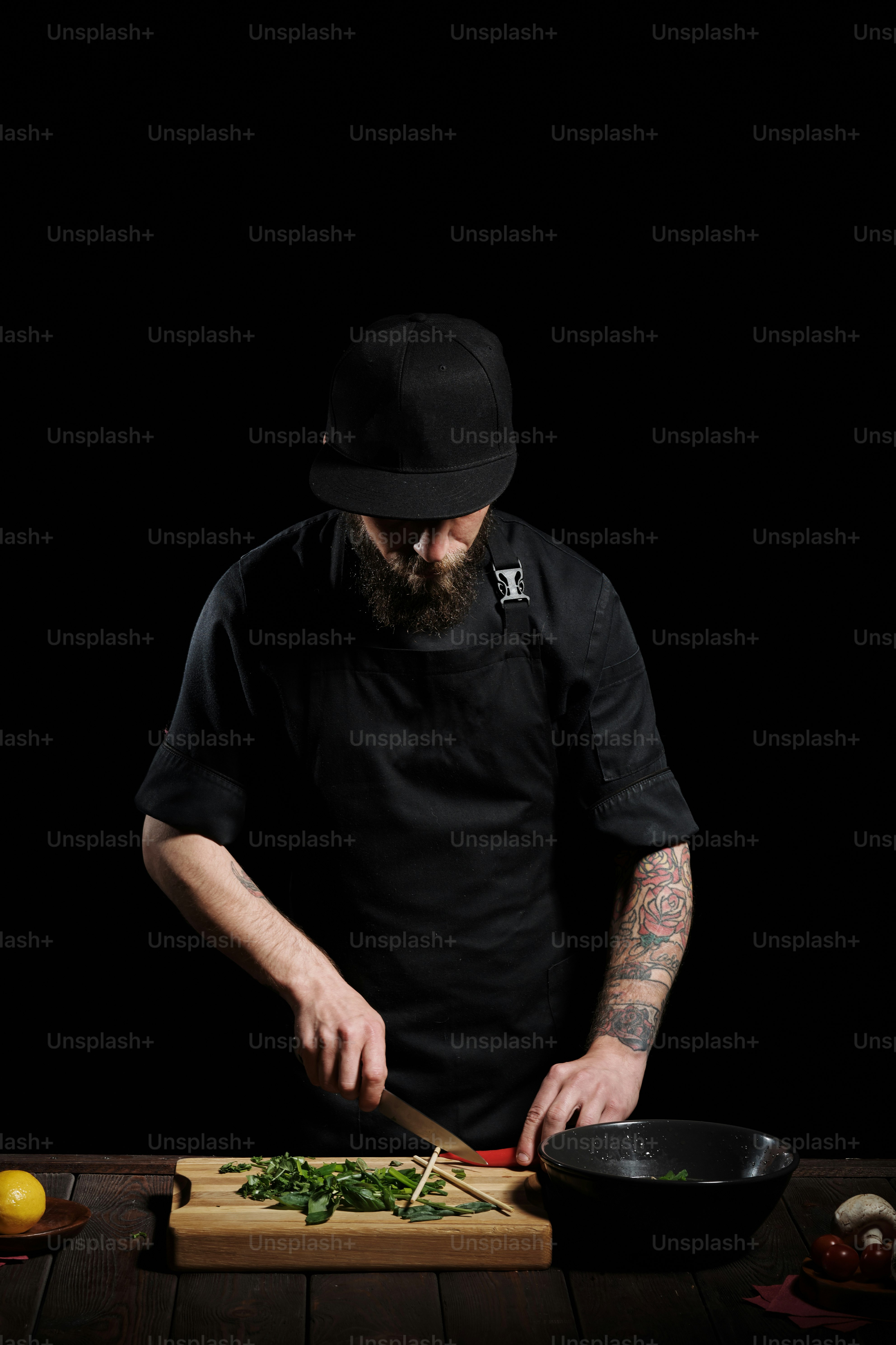 Portrait of male chef cooking pho bo in studio, cutting spicy red pepper on the board, on black background