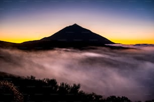 Hermoso paisaje vulcano de el teide tenerife con la cima alta y las nubes en el suelo como niebla - atemporal y parque nacional lugar escénico al aire libre - fondo coloreado y naturaleza salvaje