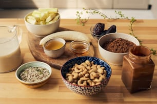 Group of bowls and jars with ingredients for smoothie on wooden kitchen table