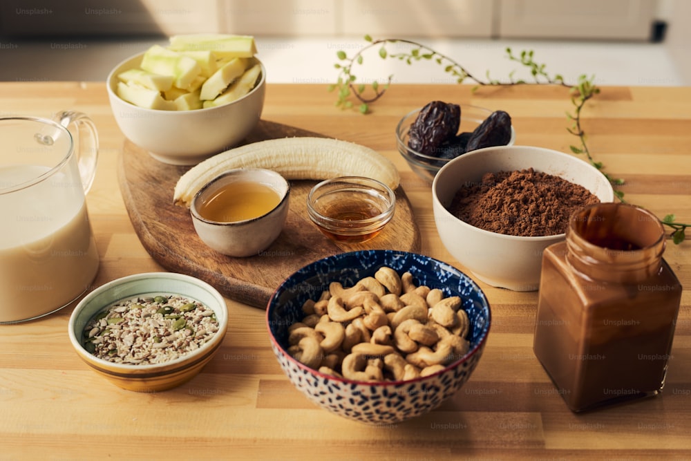 Grupo de tigelas e frascos com ingredientes para smoothie na mesa da cozinha de madeira