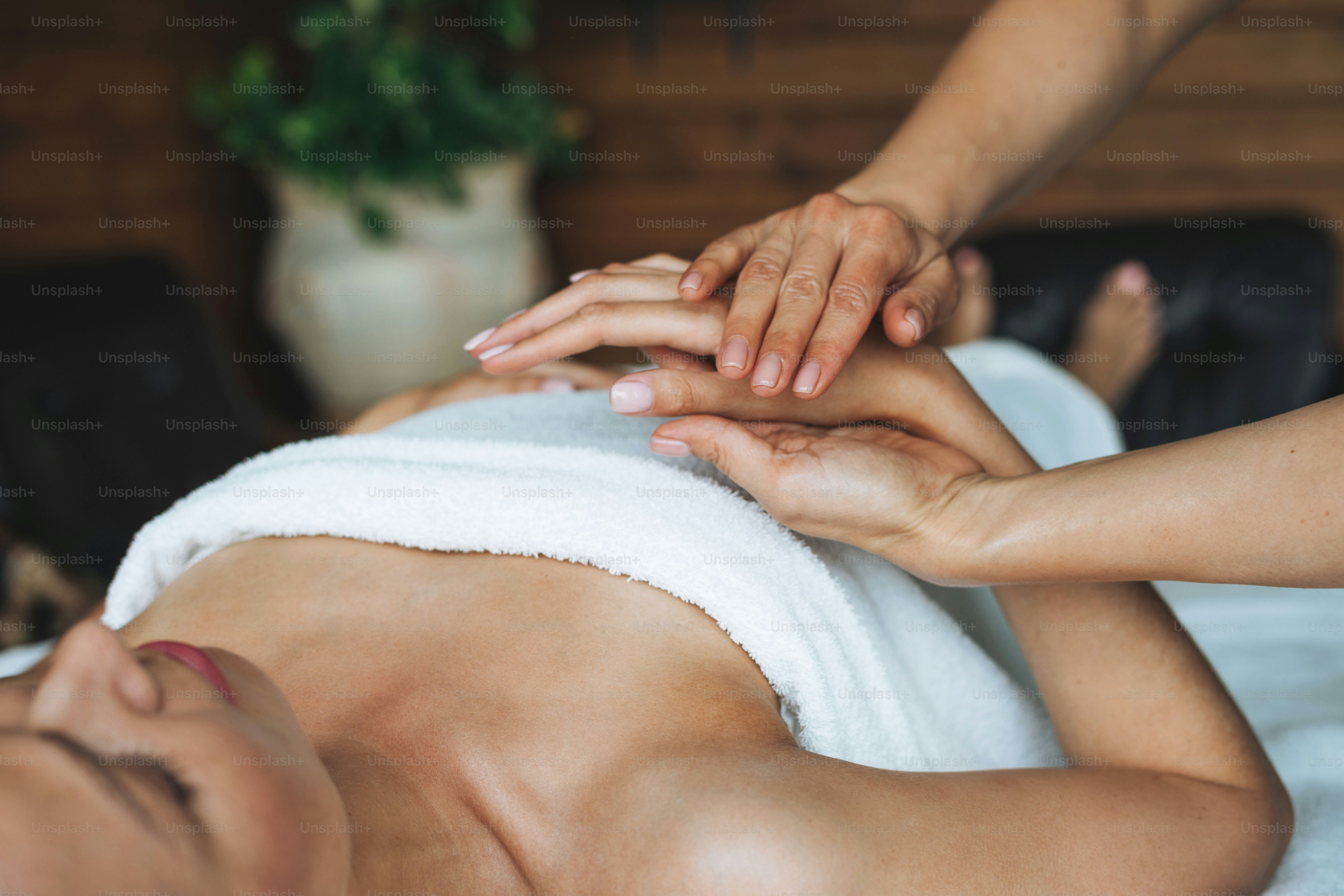 Wanita muda pirang yang menarik di sofa dengan linen putih menikmati pijat tangan di salon spa, manjakan diri Anda