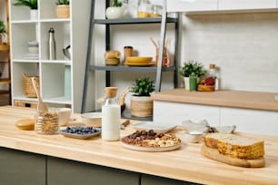 Interieur der großen Küche mit viel gesundem Essen und Flasche Milch auf Holztisch