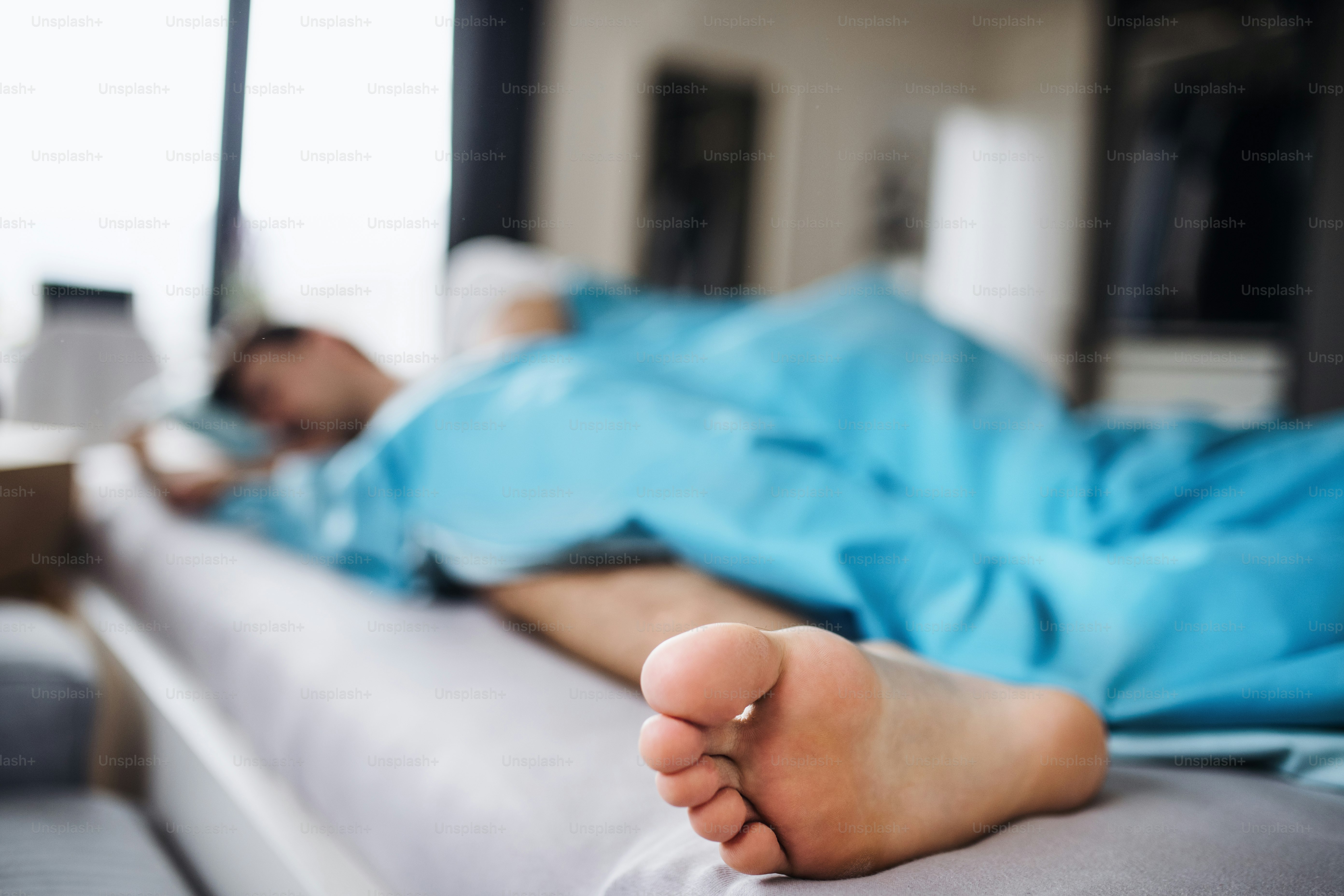 Junger Mann schläft zu Hause im Bett, eine Nahaufnahme von barfuß.