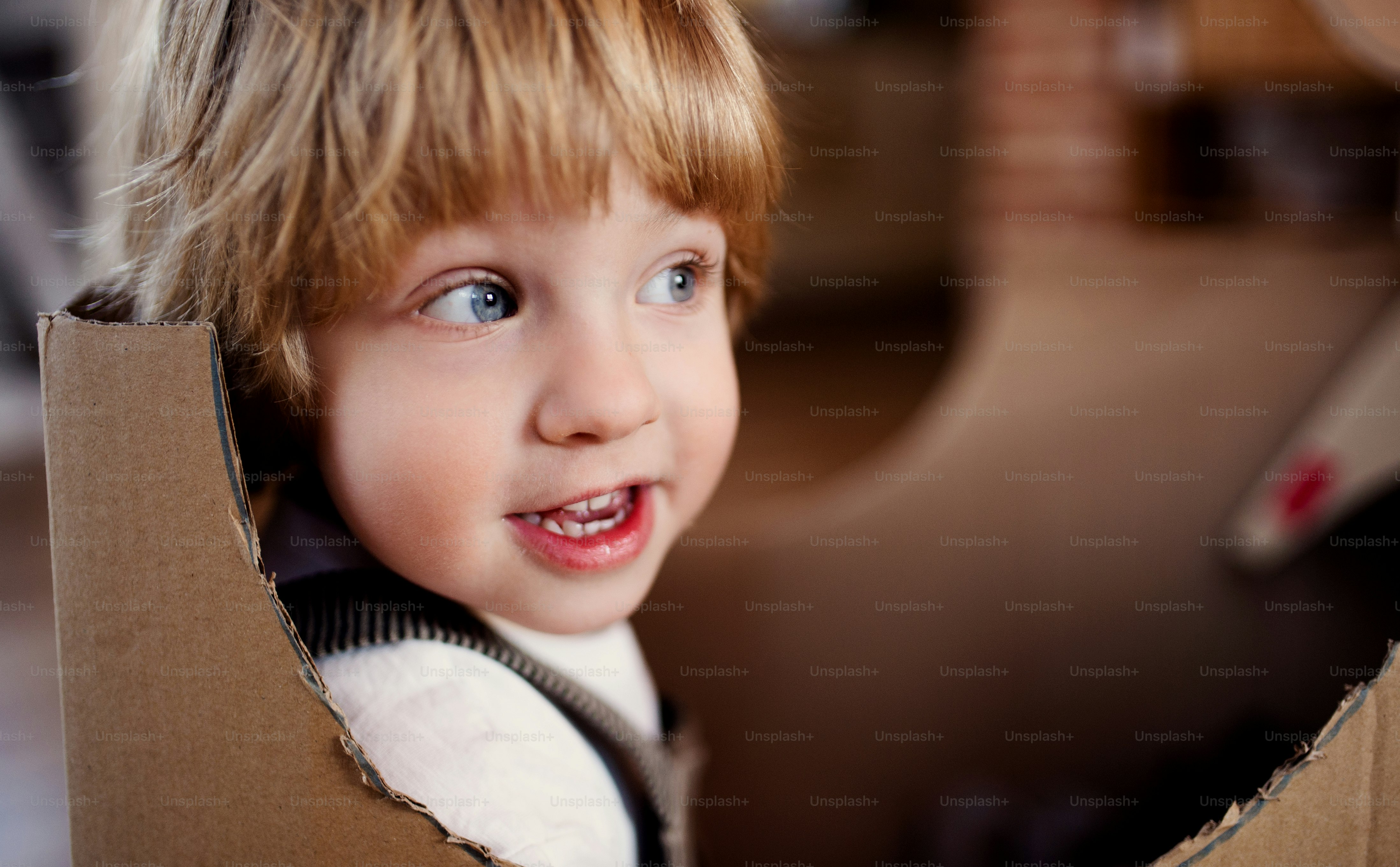 A close-up of toddler blond boy playing indoors at home. Copy space.