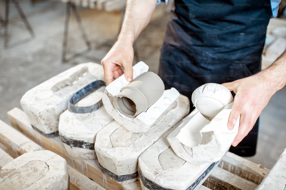陶器製造で石膏型から粘土製品を取り出す男性作業員、クローズアップ