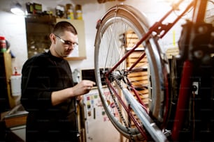 Jovem cara verificando o equilíbrio da roda da bicicleta na garagem.