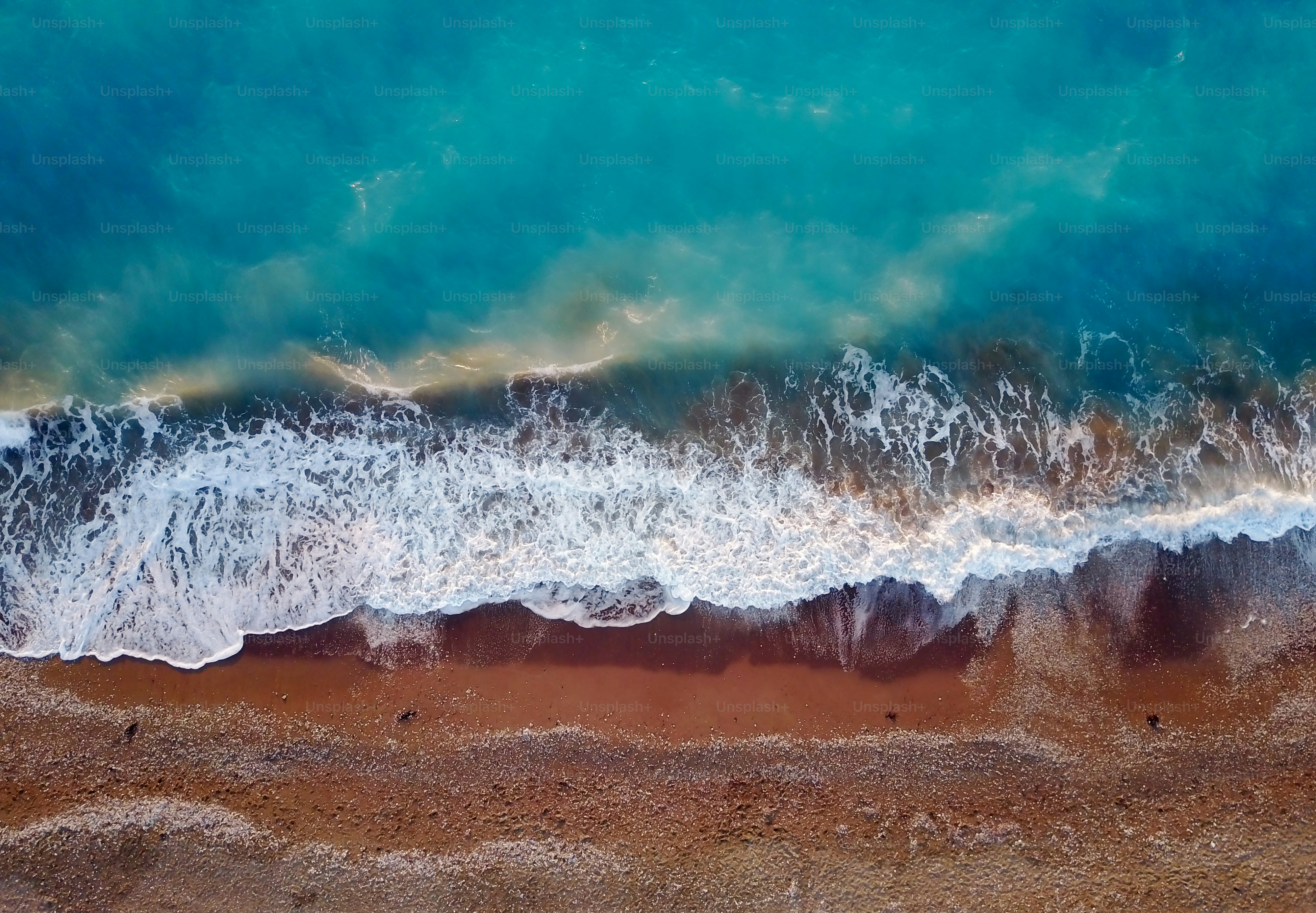 Top photo view from flying drone of tropical coral sea landscape with turquoise water and waves approaching the beach.