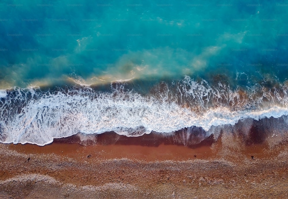 Top-Foto Ansicht von fliegender Drohne der tropischen Korallenmeereslandschaft mit türkisfarbenem Wasser und Wellen, die sich dem Strand nähern.