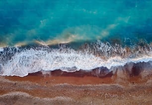 Top photo view from flying drone of tropical coral sea landscape with turquoise water and waves approaching the beach.