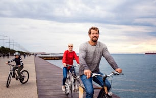 Young happy family riding bicycles outdoors on beach.
