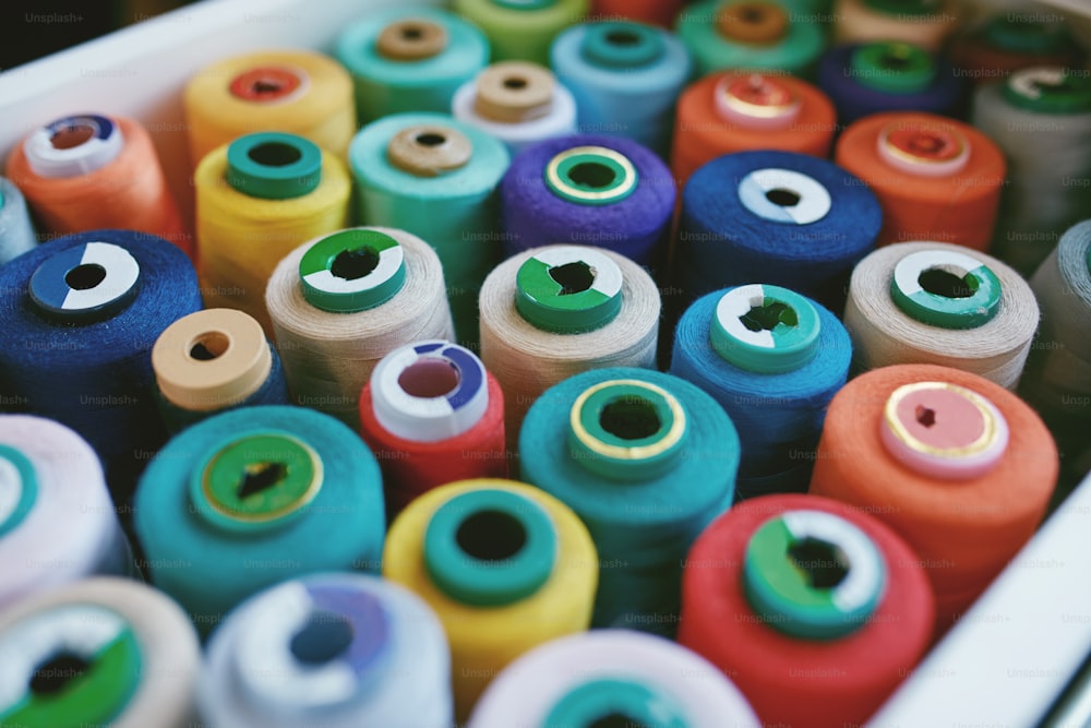 Primo piano di fili per cucire colorati nel cassetto. Primo piano di rocchetti di filo multicolore, accessori per cucire in atelier.
