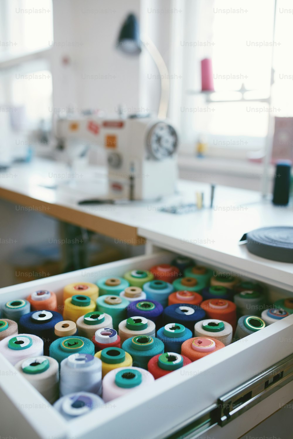 Gros plan de fils à coudre colorés dans le tiroir. Gros plan de bobines de fil multicolores, accessoires de couture dans l’atelier.