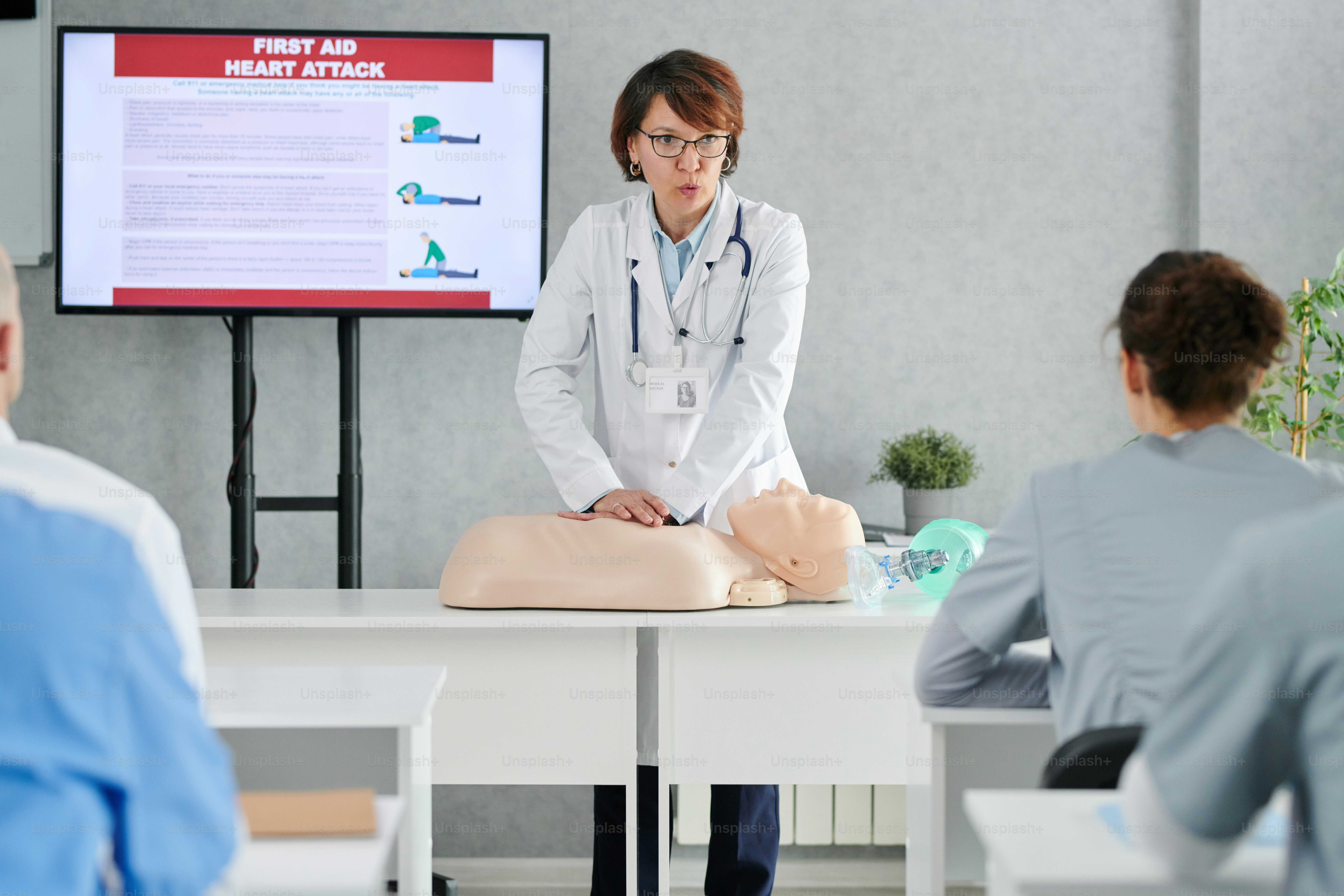 Médico especialista demonstrando em manequim como prestar primeiros socorros aos alunos em treinamento