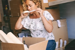 One woman closing boxes at home for moving mortgage loan activity. Female people with carton boxes packing and unpacking stuffs for a move. New home and life concept. Young lady real estate owner