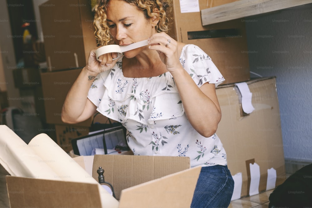 One woman closing boxes at home for moving mortgage loan activity. Female people with carton boxes packing and unpacking stuffs for a move. New home and life concept. Young lady real estate owner