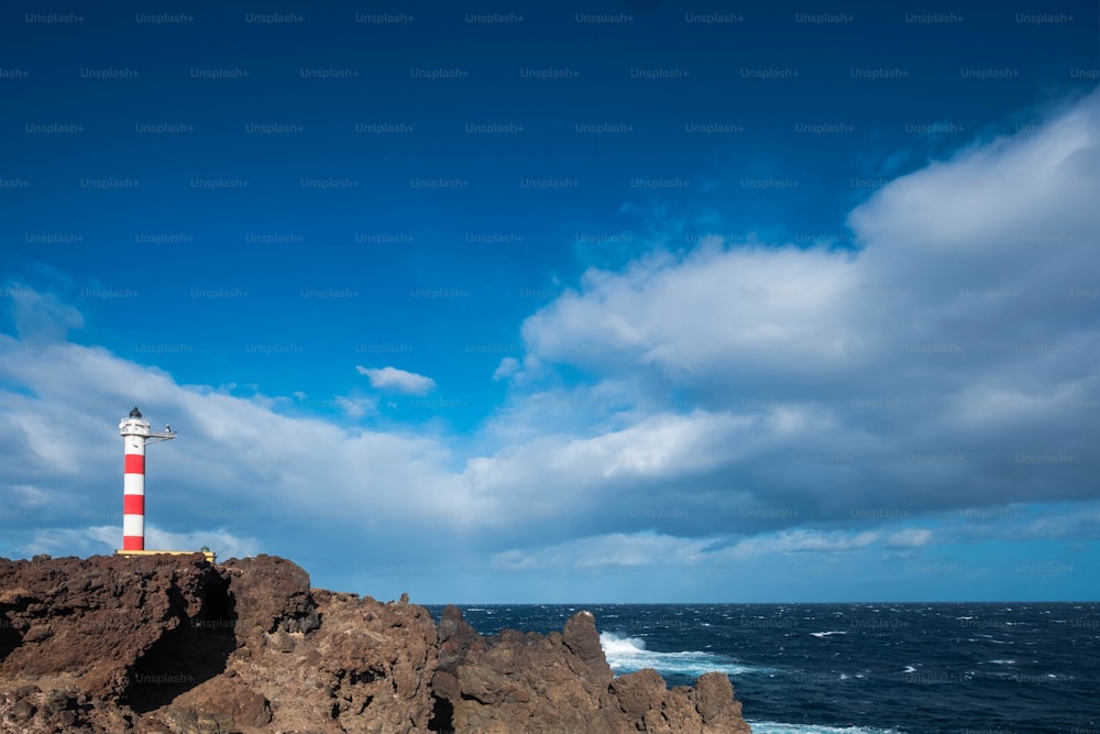 faro classico vecchio stile sulla costa di Tenerife nel mezzo dell'oceano Atlantico. Potenza dell'onda e casa isolata. Bellissimo cielo blu. Concetto di libertà.