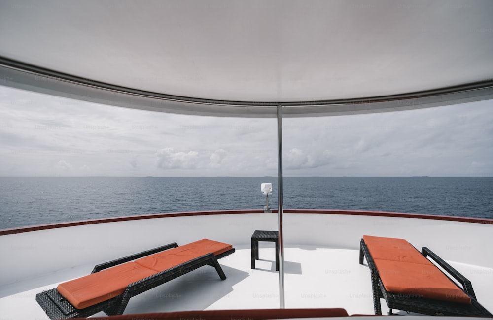 A wide-angle panoramic seascape and a Maldivian horizon in a defocused foreground viewed from the upper deck of a luxurious yacht with several recleaners in a foreground, hot sunny day, safari resort