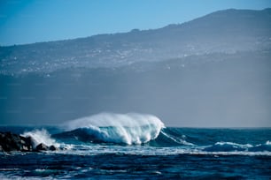 Vague parfaite unique dans l’océan bleu profond et dangereux - baril parfait pour les surfeurs courageux - côte en arrière-plan pour un lieu pittoresque touristique - profitez de la beauté du monde et de la sensation de la mer