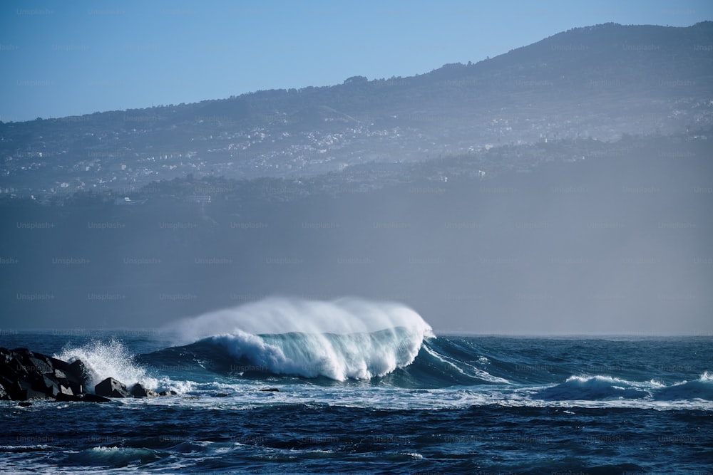 Vague parfaite unique dans l’océan bleu profond et dangereux - baril parfait pour les surfeurs courageux - côte en arrière-plan pour un lieu pittoresque touristique - profitez de la beauté du monde et de la sensation de la mer