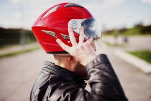 Drive safe! Rider biker man in black leather jacket put on a helmet.