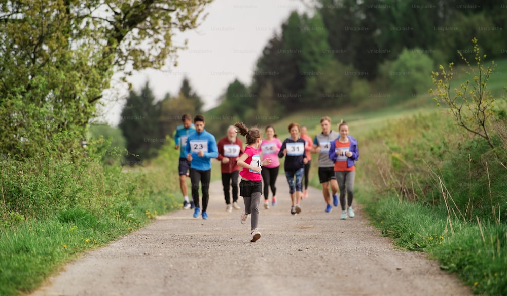 A large group of active multi generation people running a race competition in nature.