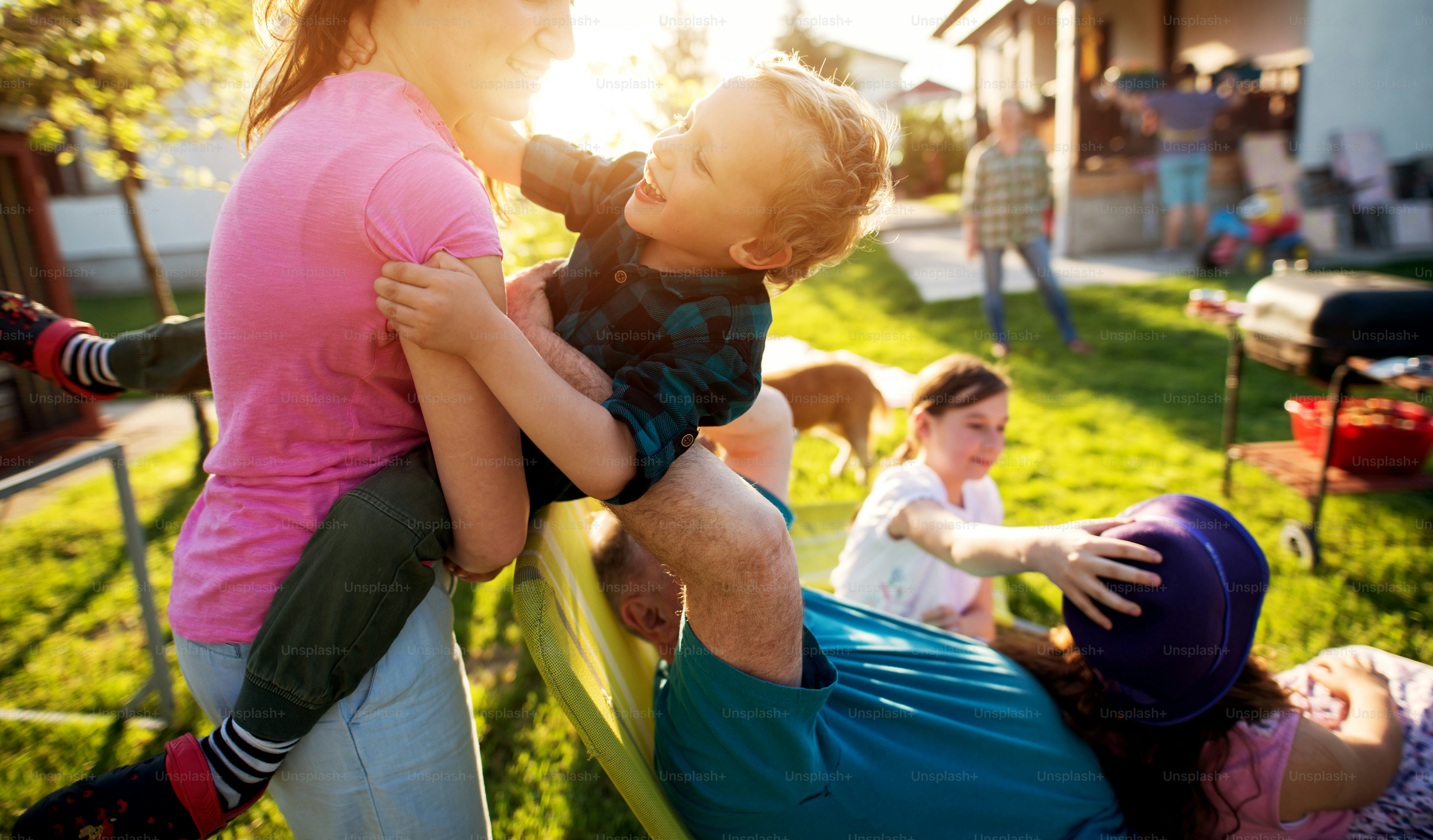 Une jeune sœur dévouée et heureuse tient son petit frère beau, joyeux et enfant, tandis que son grand-père, qui a un autre petit-enfant sur les genoux, tente de le prendre.