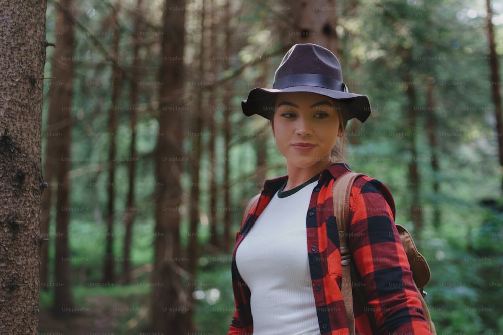 Front view of young woman on a walk in forest in summer nature, standing.
