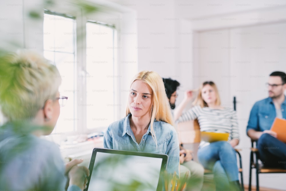 Beautiful young blonde girl speaking with a female boss on the job interview in the large bright office.