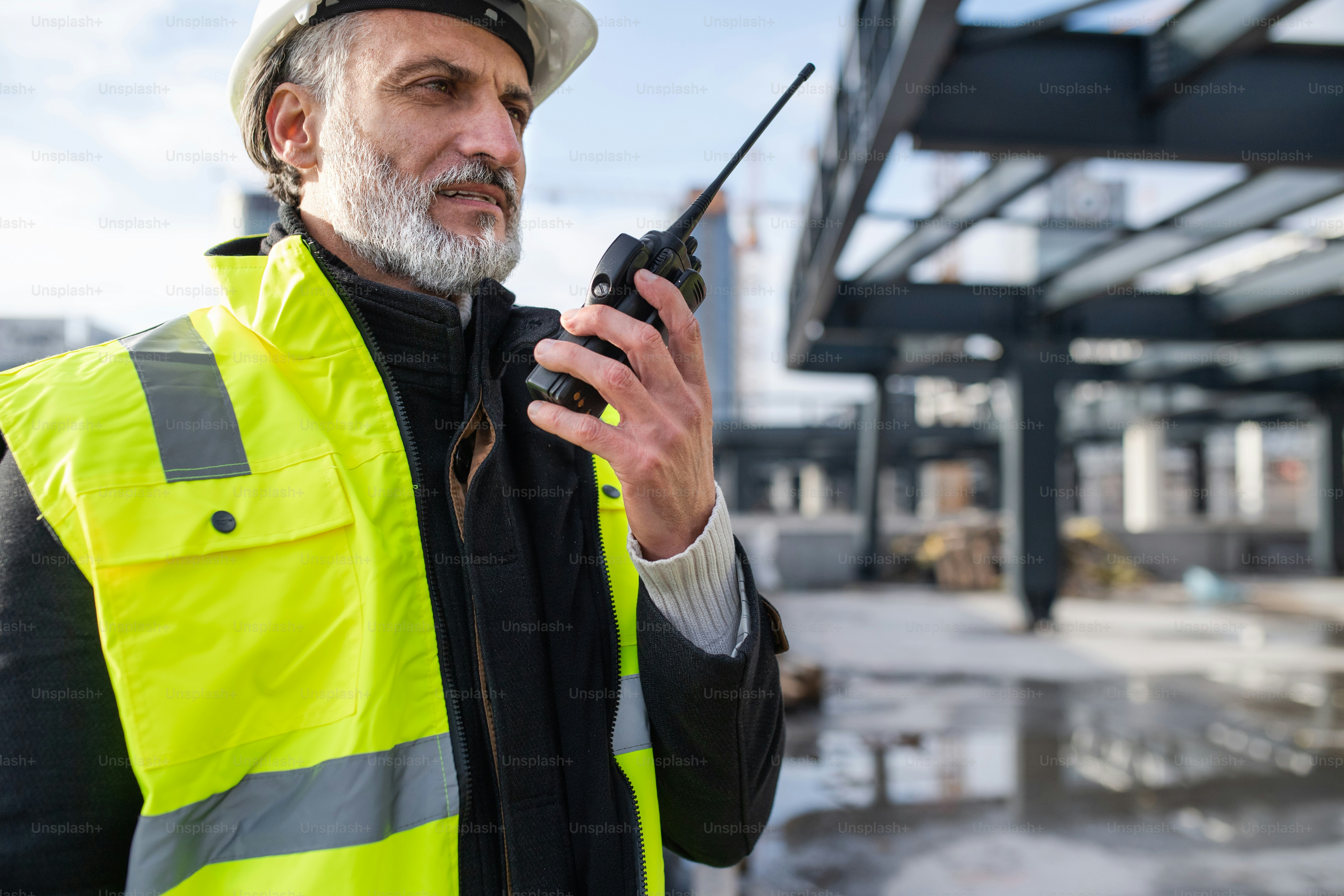 Ingeniero de hombre usando walkie talkie al aire libre en el sitio de construcción.