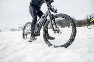 겨울에 야외에서 눈 속에서 라이딩하는 산악 자전거의 중간 부분.