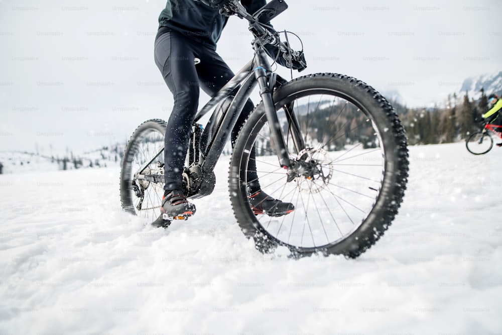 A midsection of mountain biker riding in snow outdoors in winter.