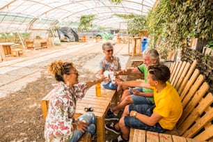 entire family from teenager to mother to grandfathers celebrate together in an outdoor bar restaurant in the nature. happiness all together with smiles and cheers. beautiful people active concept