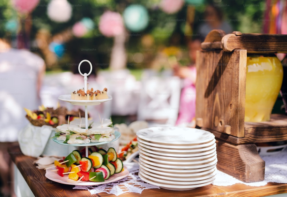 夏の庭の屋外での子供の誕生日パーティーのテーブルの上の食べ物、お祝いのコンセプト。